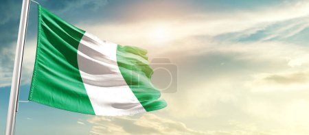 Foto de Nigeria waving flag in beautiful sky with sun - Imagen libre de derechos