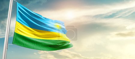 Foto de Rwanda waving flag in beautiful sky with sun - Imagen libre de derechos