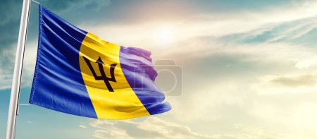 Foto de Barbados ondeando bandera en hermoso cielo con sol - Imagen libre de derechos