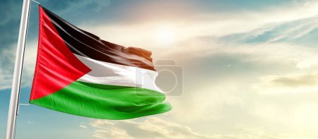 Téléchargez les photos : Drapeau national de Palestine agitant dans de beaux nuages avec le soleil - en image libre de droit