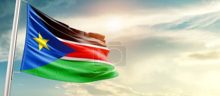 Téléchargez les photos : South Sudan waving flag in beautiful sky with sun - en image libre de droit