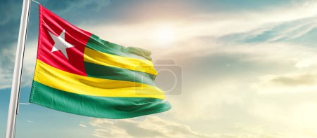 Photo for Togo waving flag in beautiful sky with sun - Royalty Free Image
