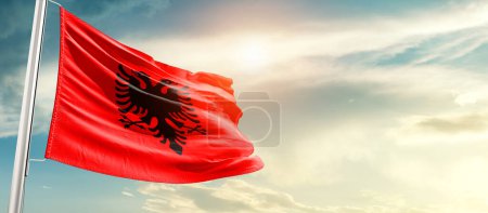 Albania waving flag in beautiful sky with sun
