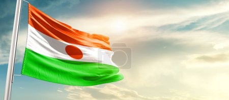 Téléchargez les photos : Niger agitant le drapeau dans un ciel magnifique avec le soleil - en image libre de droit