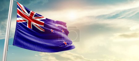 Téléchargez les photos : Drapeau de la Nouvelle-Zélande agitant dans un beau ciel avec soleil - en image libre de droit