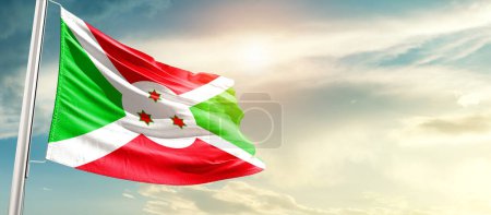 Téléchargez les photos : Burundi waving flag in beautiful sky with sun - en image libre de droit