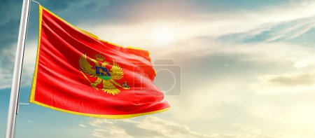Foto de Montenegro waving flag in beautiful sky with sun - Imagen libre de derechos
