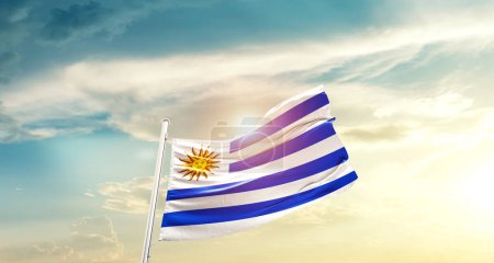 Foto de Uruguay waving flag in beautiful sky with sun - Imagen libre de derechos