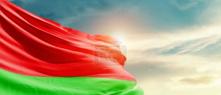 Téléchargez les photos : Biélorussie agitant drapeau dans un ciel magnifique avec soleil - en image libre de droit