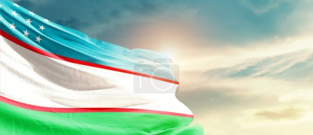 Foto de Uzbekistán ondeando bandera en hermoso cielo con sol - Imagen libre de derechos