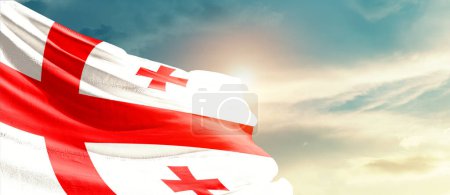 Photo for Georgia waving flag in beautiful sky with sun - Royalty Free Image