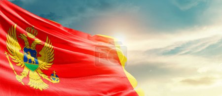 Téléchargez les photos : Monténégro agitant le drapeau dans un ciel magnifique avec le soleil - en image libre de droit