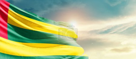 Téléchargez les photos : Togo waving flag in beautiful sky with sun - en image libre de droit