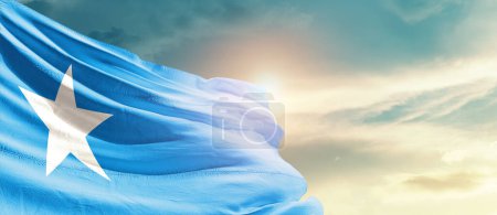 Téléchargez les photos : Somalie agitant le drapeau dans un ciel magnifique avec le soleil - en image libre de droit
