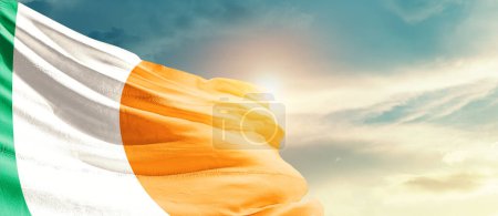 Irlanda ondeando bandera en hermoso cielo con sol