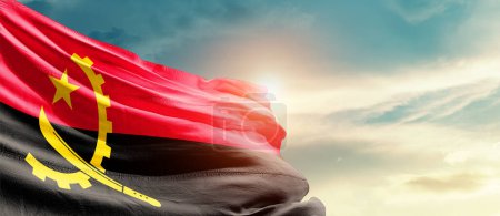 Téléchargez les photos : Angola agitant le drapeau dans un ciel magnifique avec le soleil - en image libre de droit