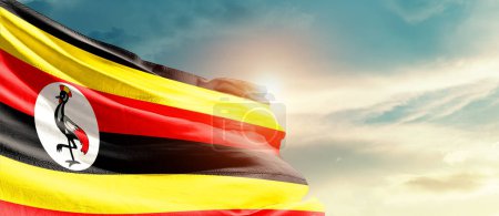 Foto de Uganda ondeando bandera en hermoso cielo con sol - Imagen libre de derechos