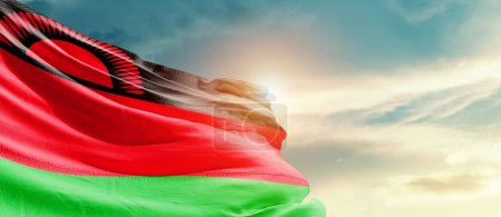 Téléchargez les photos : Malawi agitant le drapeau dans un ciel magnifique avec le soleil - en image libre de droit