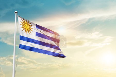 Photo for Uruguay waving flag in beautiful sky with sun - Royalty Free Image