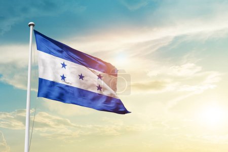 Téléchargez les photos : Honduras waving flag in beautiful sky with sun - en image libre de droit