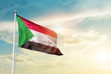 Sudan waving flag in beautiful sky with sun