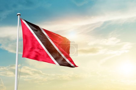 Téléchargez les photos : Trinité-et-Tobago agitant le drapeau dans un ciel magnifique avec le soleil - en image libre de droit
