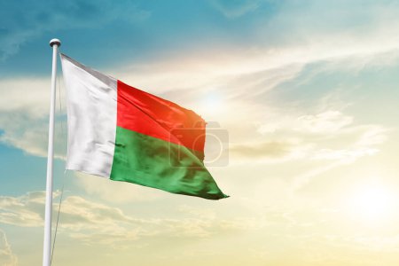 Photo for Madagascar waving flag in beautiful sky with sun - Royalty Free Image
