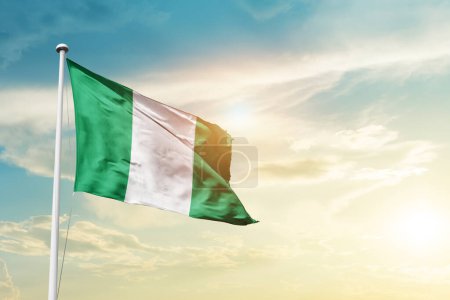 Téléchargez les photos : Nigéria agitant drapeau dans un ciel magnifique avec soleil - en image libre de droit