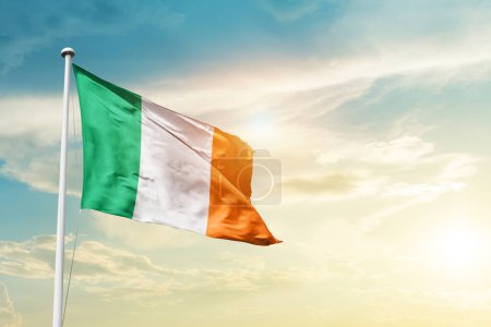 Téléchargez les photos : Irlande agitant le drapeau dans un ciel magnifique avec le soleil - en image libre de droit
