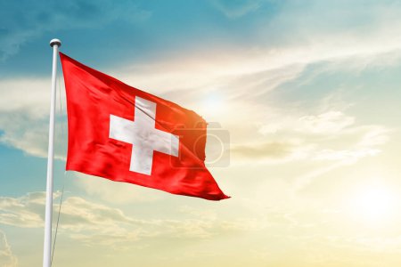 Téléchargez les photos : Switzerland waving flag in beautiful sky with sun - en image libre de droit
