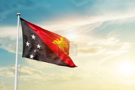 Photo for Papua New Guinea waving flag in beautiful sky with sun - Royalty Free Image