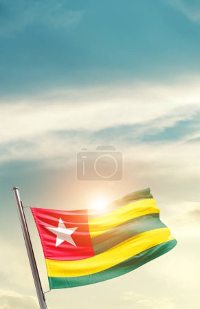 Téléchargez les photos : Togo agitant drapeau dans un ciel magnifique avec soleil - en image libre de droit