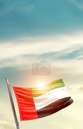 Téléchargez les photos : United Arab Emirates waving flag in beautiful sky with sun - en image libre de droit