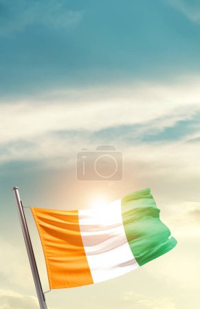 Photo for Ivory island waving flag in beautiful sky with sun - Royalty Free Image