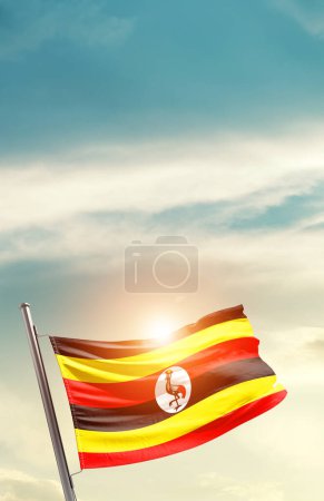 Foto de Uganda waving flag in beautiful sky with sun - Imagen libre de derechos