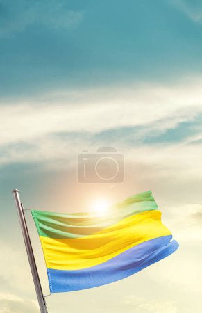 Téléchargez les photos : Drapeau du Gabon agitant dans un ciel magnifique avec soleil - en image libre de droit
