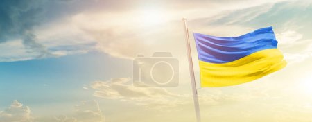 Foto de Ucrania ondeando bandera en el hermoso cielo con sol - Imagen libre de derechos