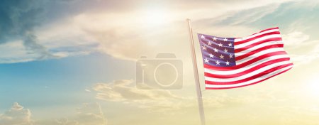 Foto de Estados Unidos ondeando bandera en hermoso cielo con sol - Imagen libre de derechos