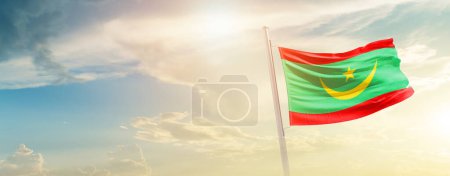 Téléchargez les photos : Mauritanie agitant le drapeau dans un ciel magnifique avec le soleil - en image libre de droit