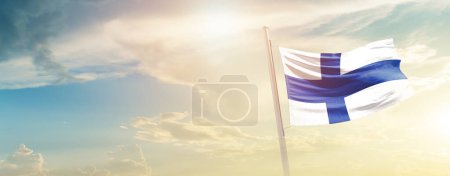 Finlandia ondeando bandera en hermoso cielo con sol