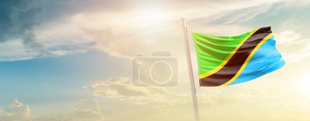 Tanzania waving flag in beautiful sky with sun