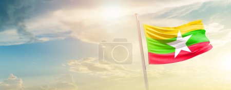 Photo for Myanmar  waving flag in beautiful sky with sun - Royalty Free Image