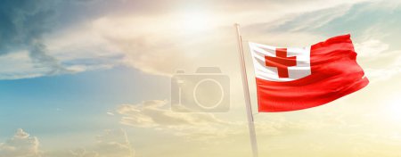 Foto de Tonga ondeando bandera en el hermoso cielo con sol - Imagen libre de derechos