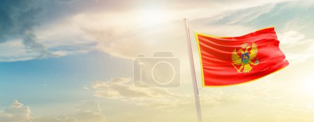 Foto de Montenegro ondeando bandera en hermoso cielo con sol - Imagen libre de derechos