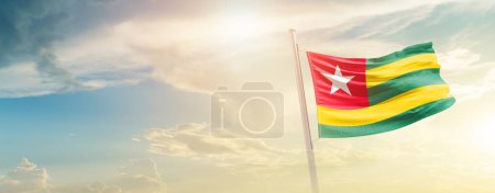 Téléchargez les photos : Togo agitant drapeau dans un ciel magnifique avec soleil - en image libre de droit