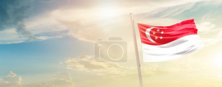 Photo for Singapore waving flag in beautiful sky with sun - Royalty Free Image