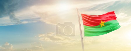 Téléchargez les photos : Drapeau du Burkina Faso agitant un beau ciel avec soleil - en image libre de droit