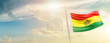 Téléchargez les photos : Bolivia waving flag in beautiful sky with sun - en image libre de droit