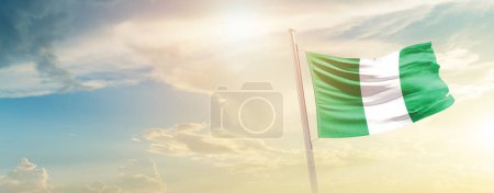 Téléchargez les photos : Nigéria agitant drapeau dans un ciel magnifique avec soleil - en image libre de droit