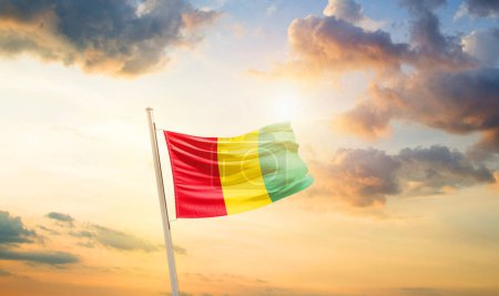 Téléchargez les photos : Drapeau de Guinée dans un ciel magnifique avec nuages et soleil - en image libre de droit